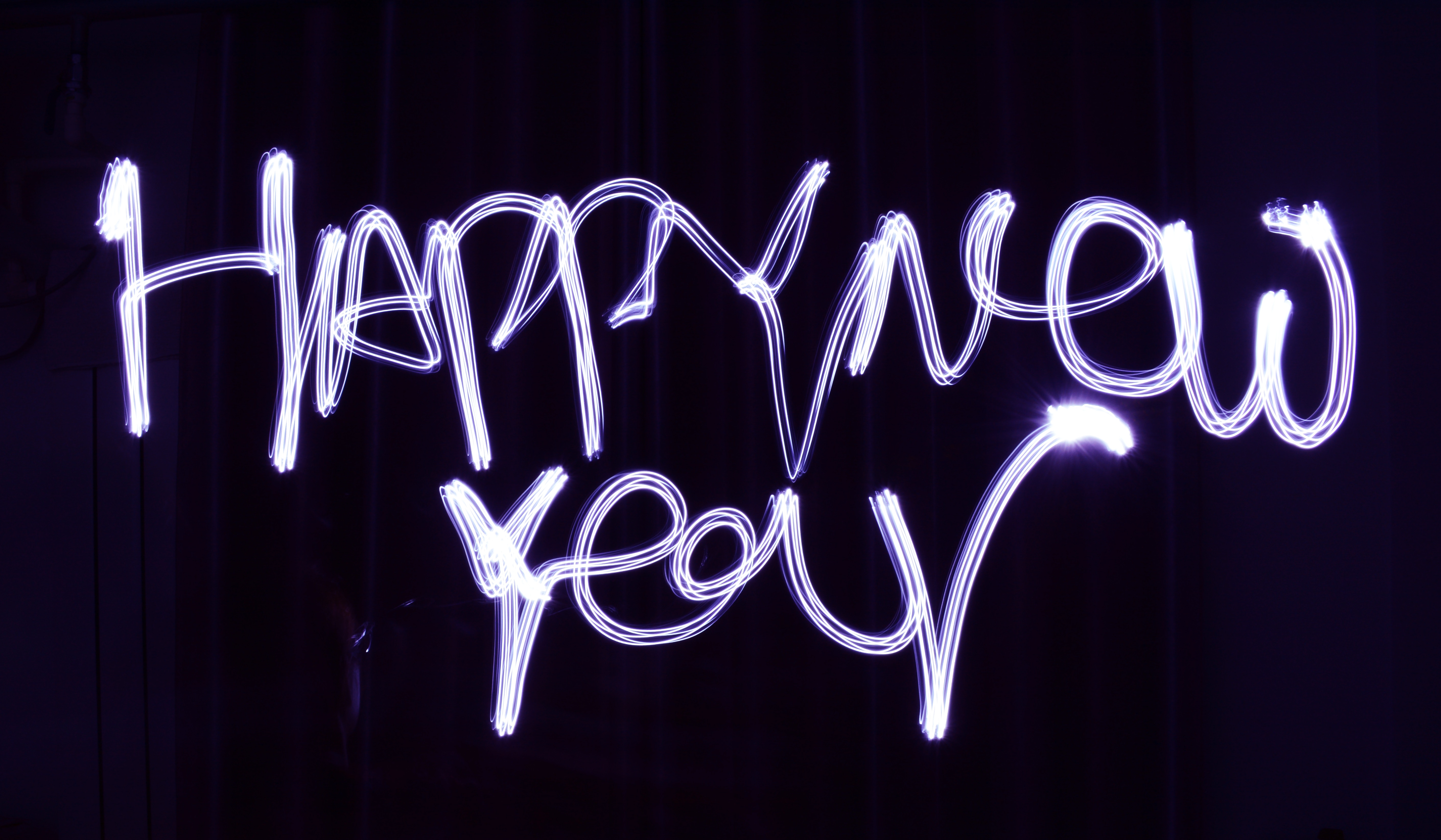 Happy New year written with a purple sparkler on a black background