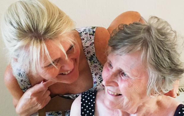 An older woman and her daughter sit laughing together
