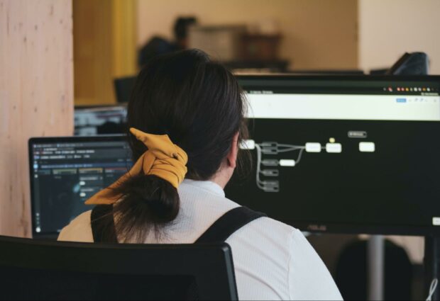 Women at a desk working with two computer screens.