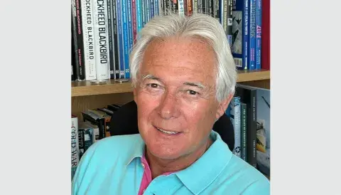 Headshot of Paul Crickmore, in front of a bookcase