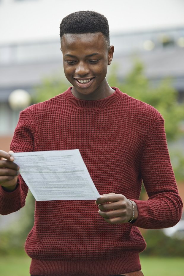Student looking happy with a piece of paper showing his results