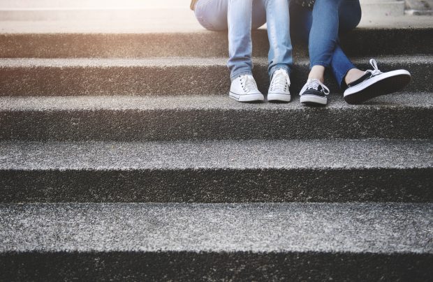 some people sitting on steps. only their legs and feet are in shot.