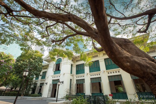 Photograph of the frontage of the British Embassy Bangkok, March 2019 (Kridtidej Sawangcharoen). There is a far spreading tree in the foreground and the Embassy building is very impressive.