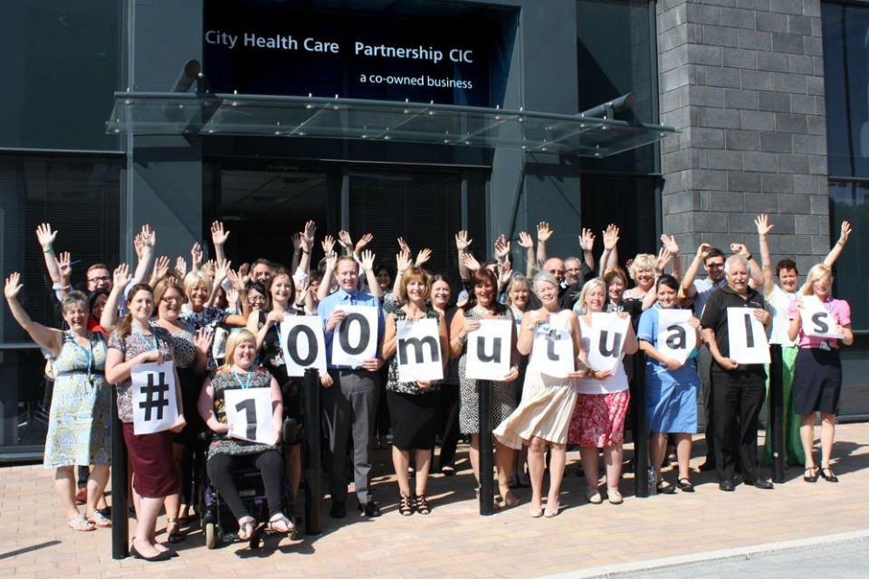staff from a mutual society waving and holding a banner reading '#100 mutuals'