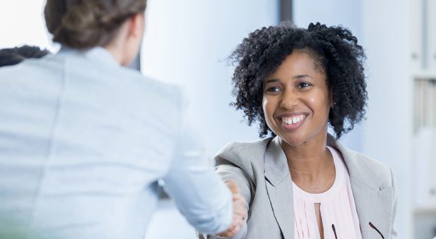Confident interviewer greets potential employee before job interview.