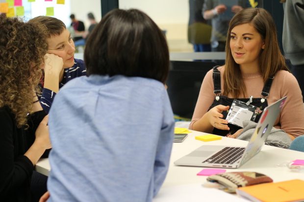 An image of 4 people in discussion at a table