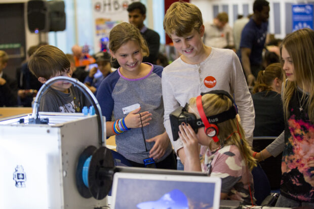 2 children looking on to a 3rd child with a virtual reality headset on at Dragon Hall