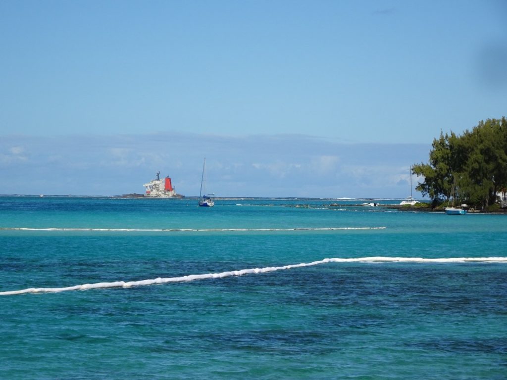 Photo of coast with shipwreck and booms in background