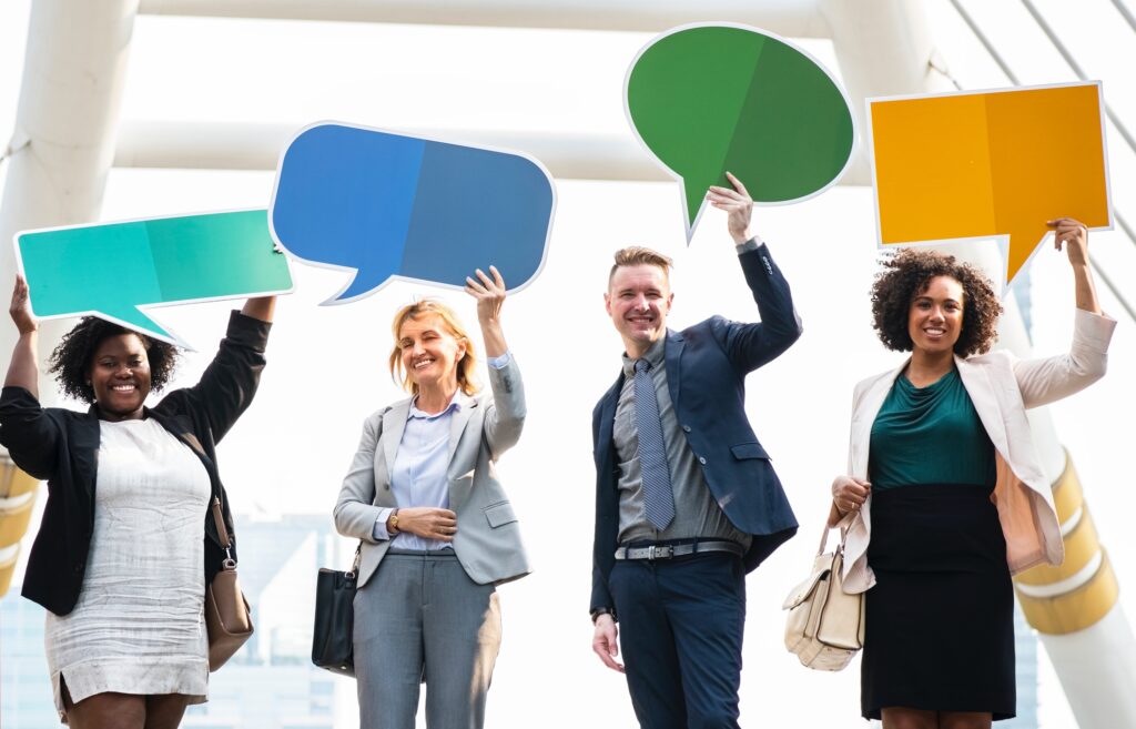 Four people holding up cardboard speech bubbles