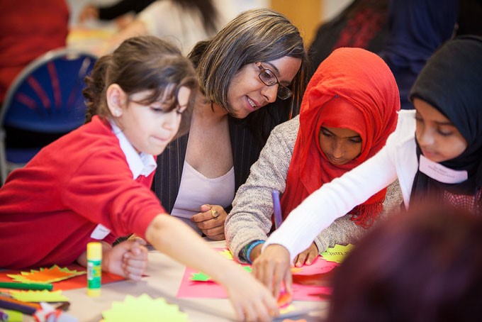 Woman watching encouragingly as children write