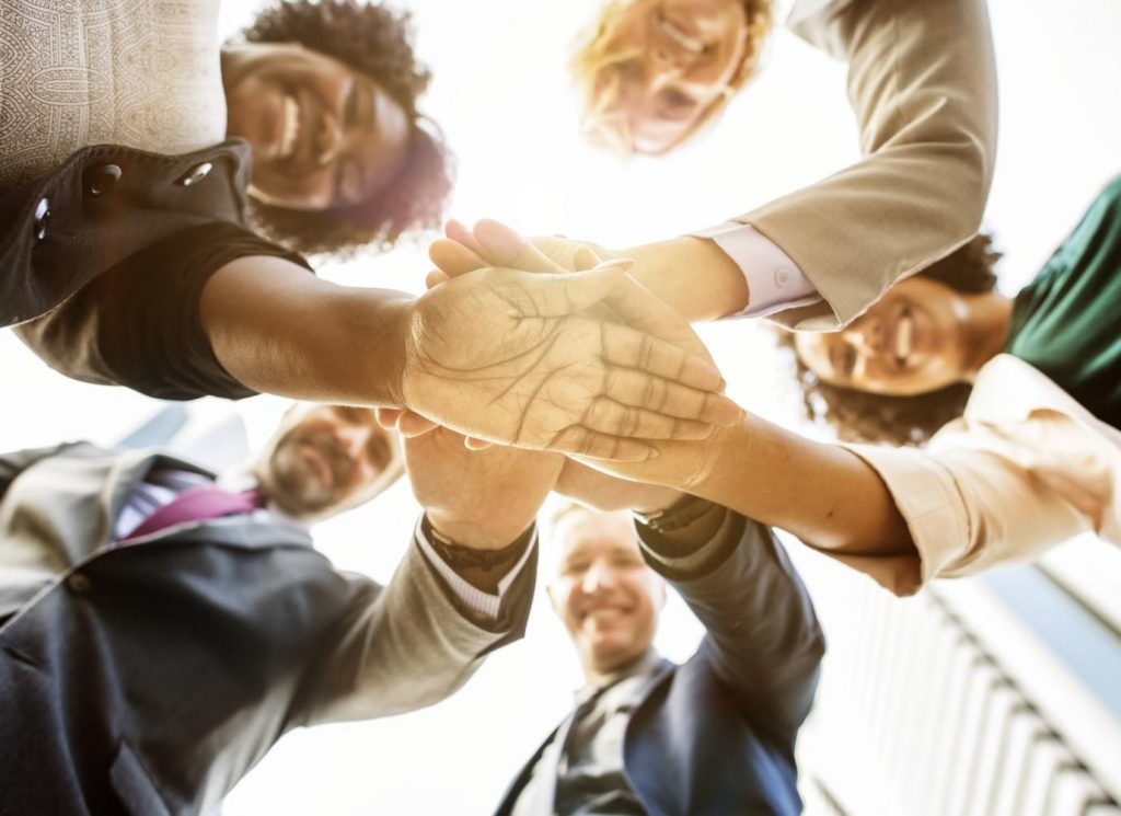 5 people joining hands in agreement