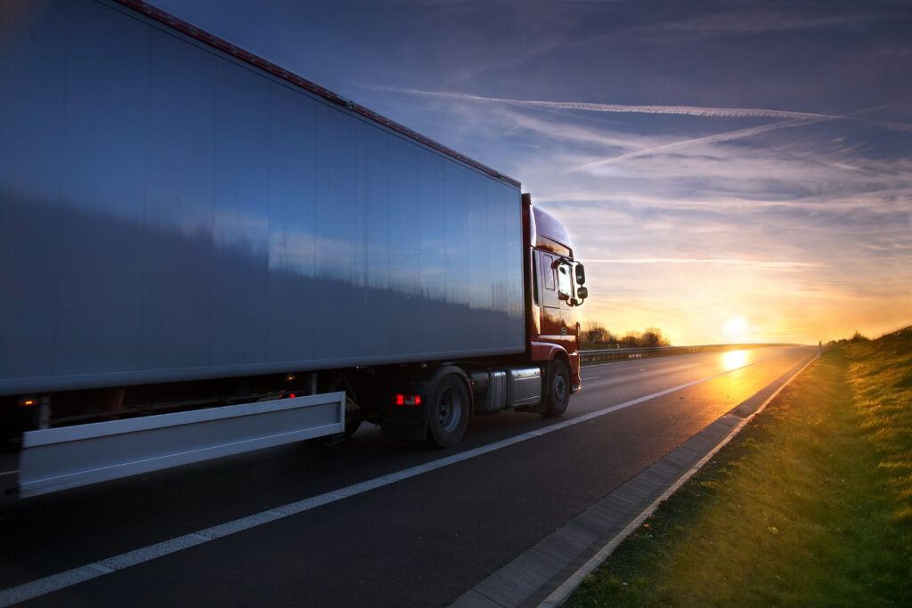 Lorry with a trailer driving along the road into a sunset