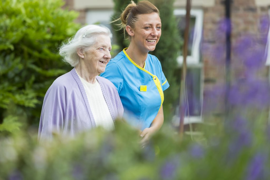 Female resident and care team member walking in the gardens
