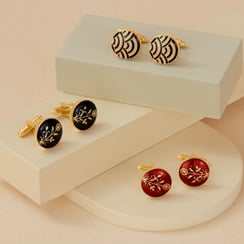 Azga enamel jewellery Three enamel cufflinks propped up on small beige plinths.