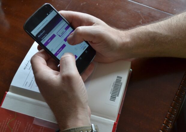 Using a library app on a smartphone to renew a library book at home.