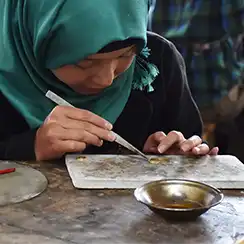 Turquoise Mountain jewellery artisan A jewellery artisan wearing a green veil works on a piece of jewellery.