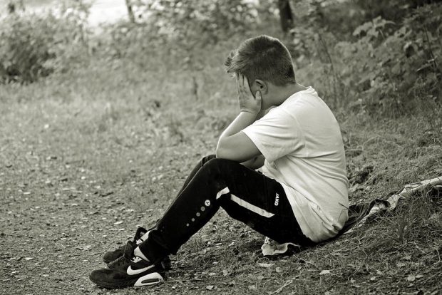 Boy sat alone with head in hands