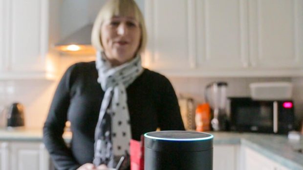 Woman in her kitchen using a voice activated gadget