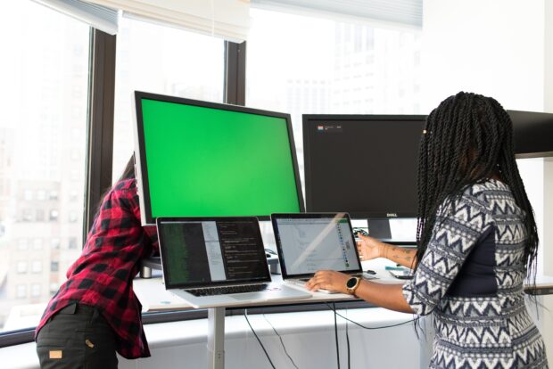 Rear view on two women working on laptops and additional monitors