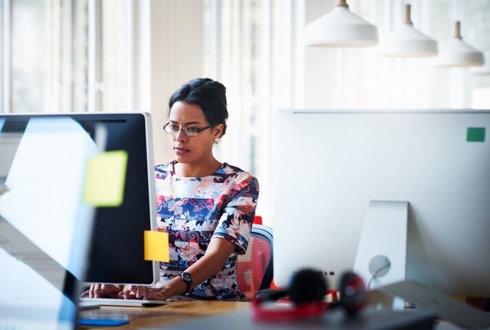 Women using computer with post-it notes on side of screen