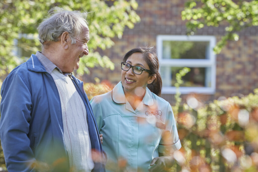 Man and care home colleague walking in care home garden.