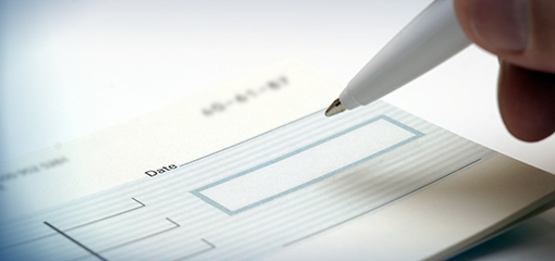 Someone's pen and hand filling in a cheque