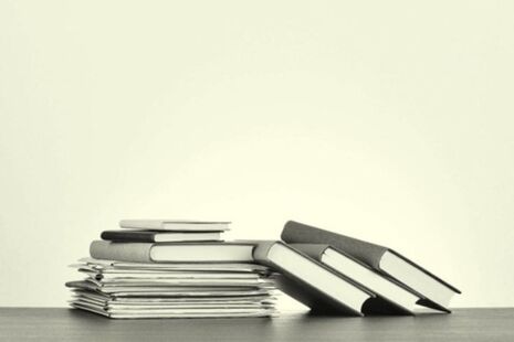 Stack of published advisory committee reports and documents on a desk.