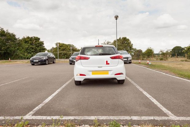 White car with 'L' plates, parked in bay