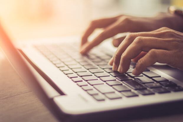 image of a person typing on a laptop keyboard
