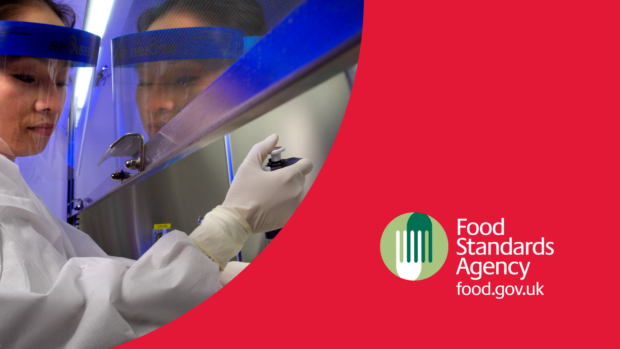 A person in PPE including a full face mask, overalls and gloves holds a syringe. Red background and Food Standards Agency logo in bottom right.