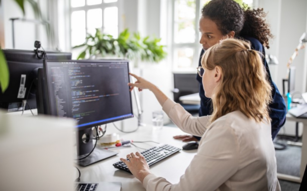 2 women looking at a computer screen full of code