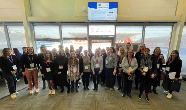 A group of 30 women stood by a window.