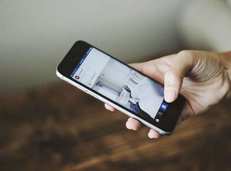 Smartphone user holds phone in hand, screen showing image of a bedroom.