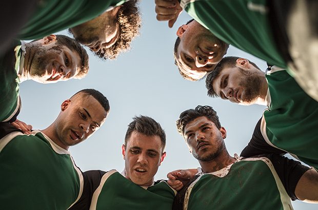 A rugby team huddle of players.