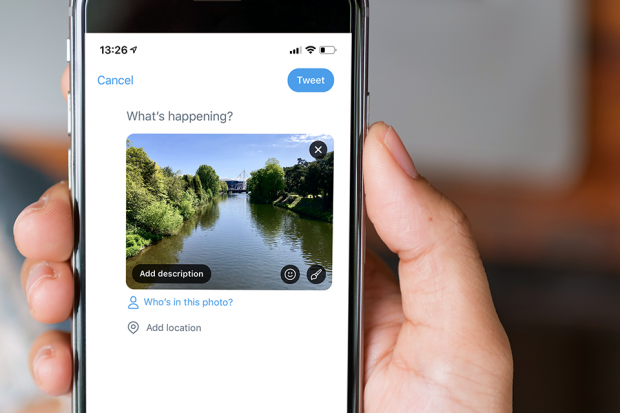 A hand holding a smartphone showing the 'add image description' link.