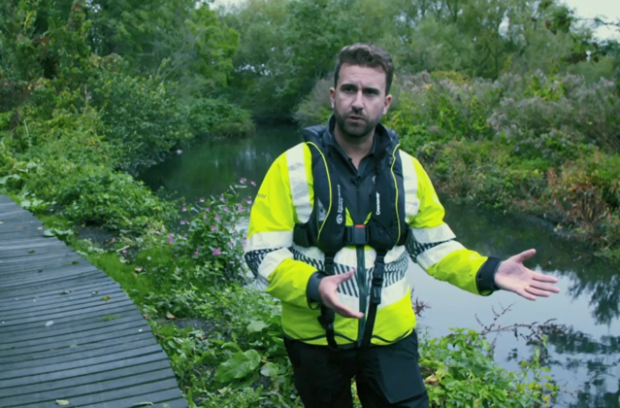 Environment Agency officer Mathew Reed explains his work investigating Symphony Chauffeurs, standing next to a body of water wearing a high vis jacket.