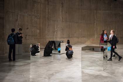 Several students examine four large, mirrored cubes