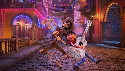 A boy and a skeleton dance joyfully on a cobblestone street at night, surrounded by colourful lights and festive decorations