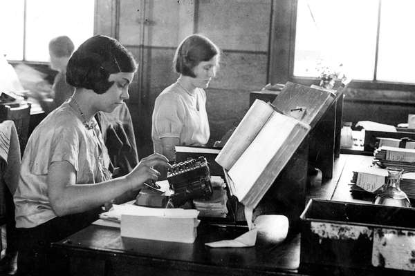 black and white photo of two women working at a desk with punch cards