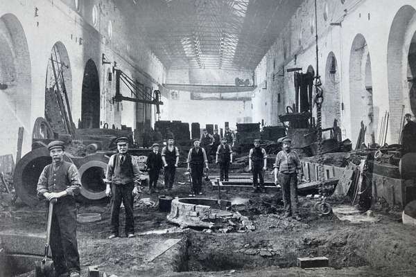 Black and white photo of a group of men working in a foundry