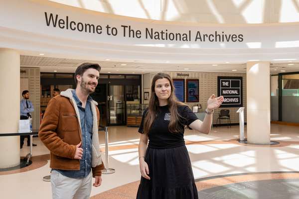 A member of National Archives staff greets a visitor in the welcome hall, a large airy space.