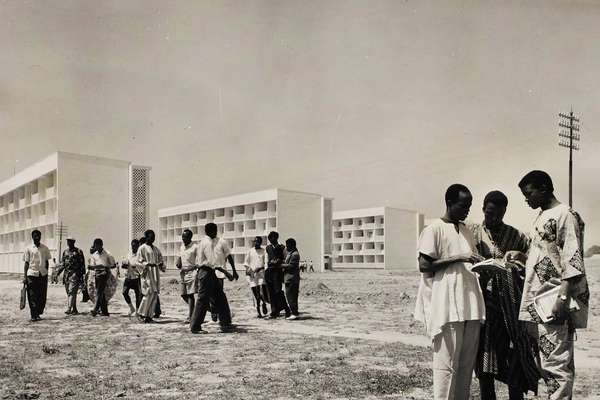A black and white photo of people standing in front of buildings