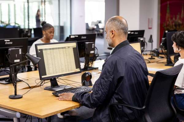 A person sits doing research at a bank of computers.
