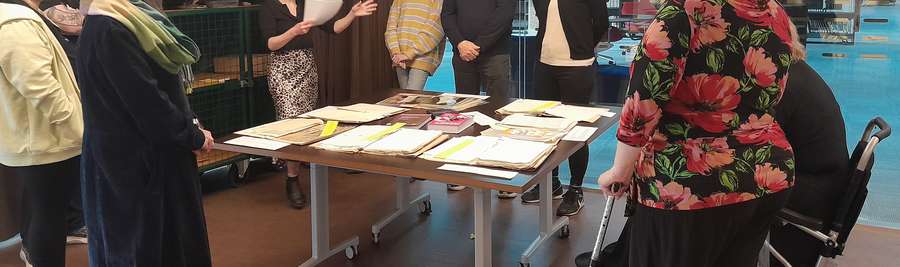 A group of people around a table looking at and discussion archival records.