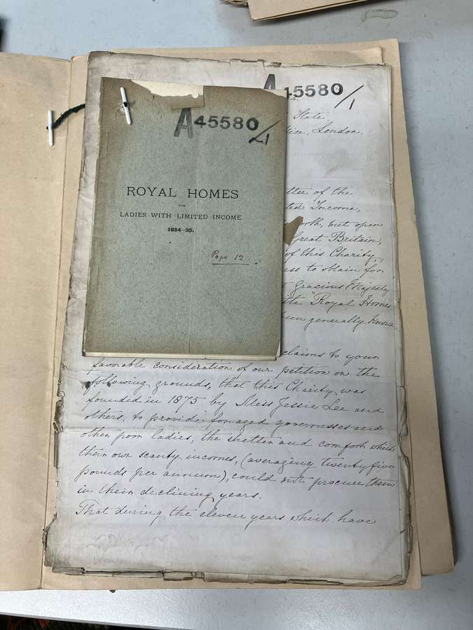 A handwritten document below a booklet titled 'Royal Homes for Ladies With Limited Income'