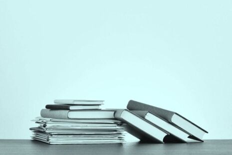 Stack of published advisory committee reports and documents on a desk.