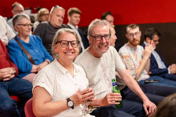 Two visitors smiling while sitting in the crowd at the auditorium at The National Archives.
