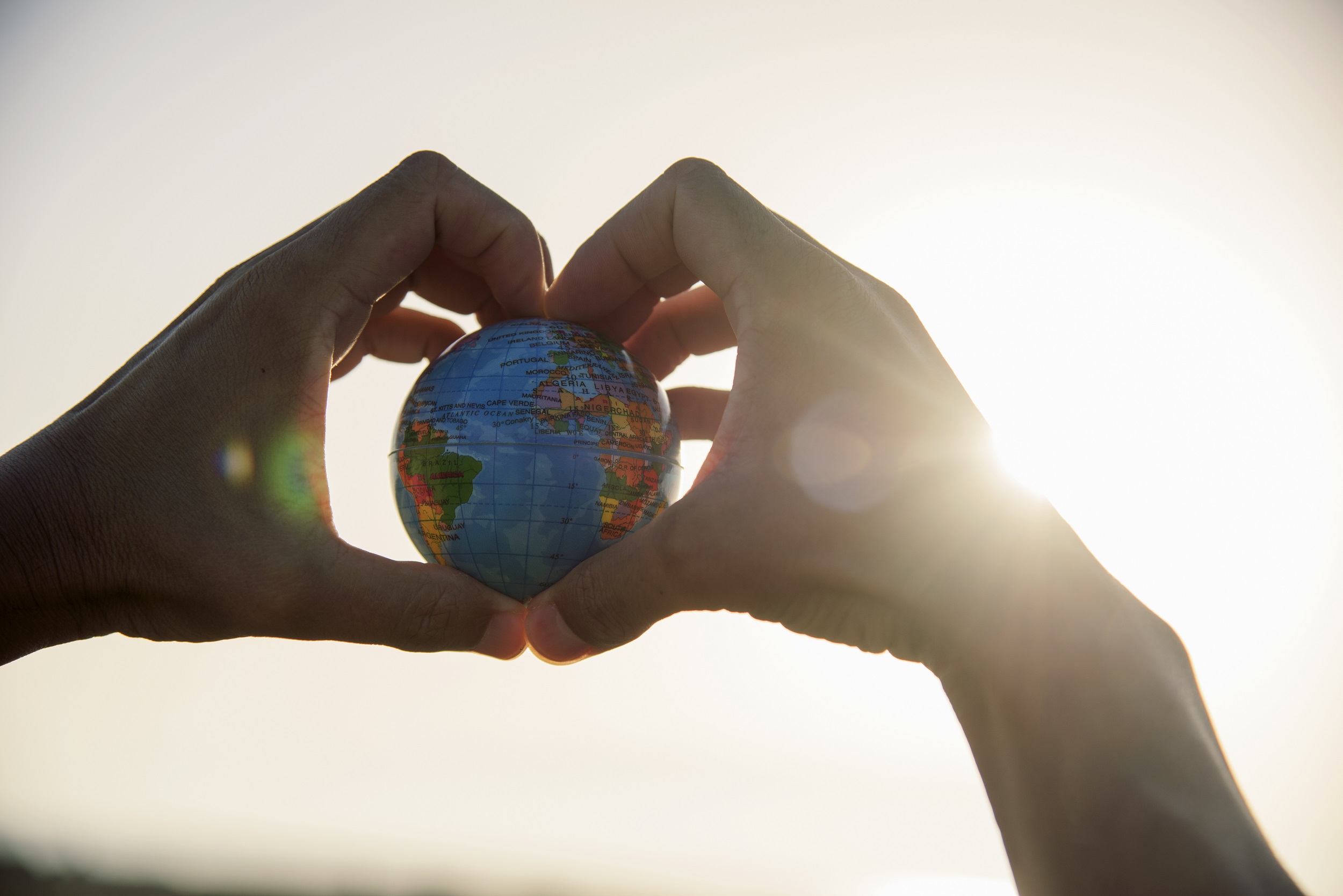 Hands holding a small globe.