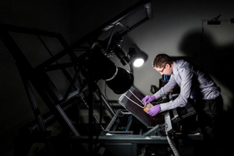 A person digitising a document in a dark room, with two spotlights focused on the document.
