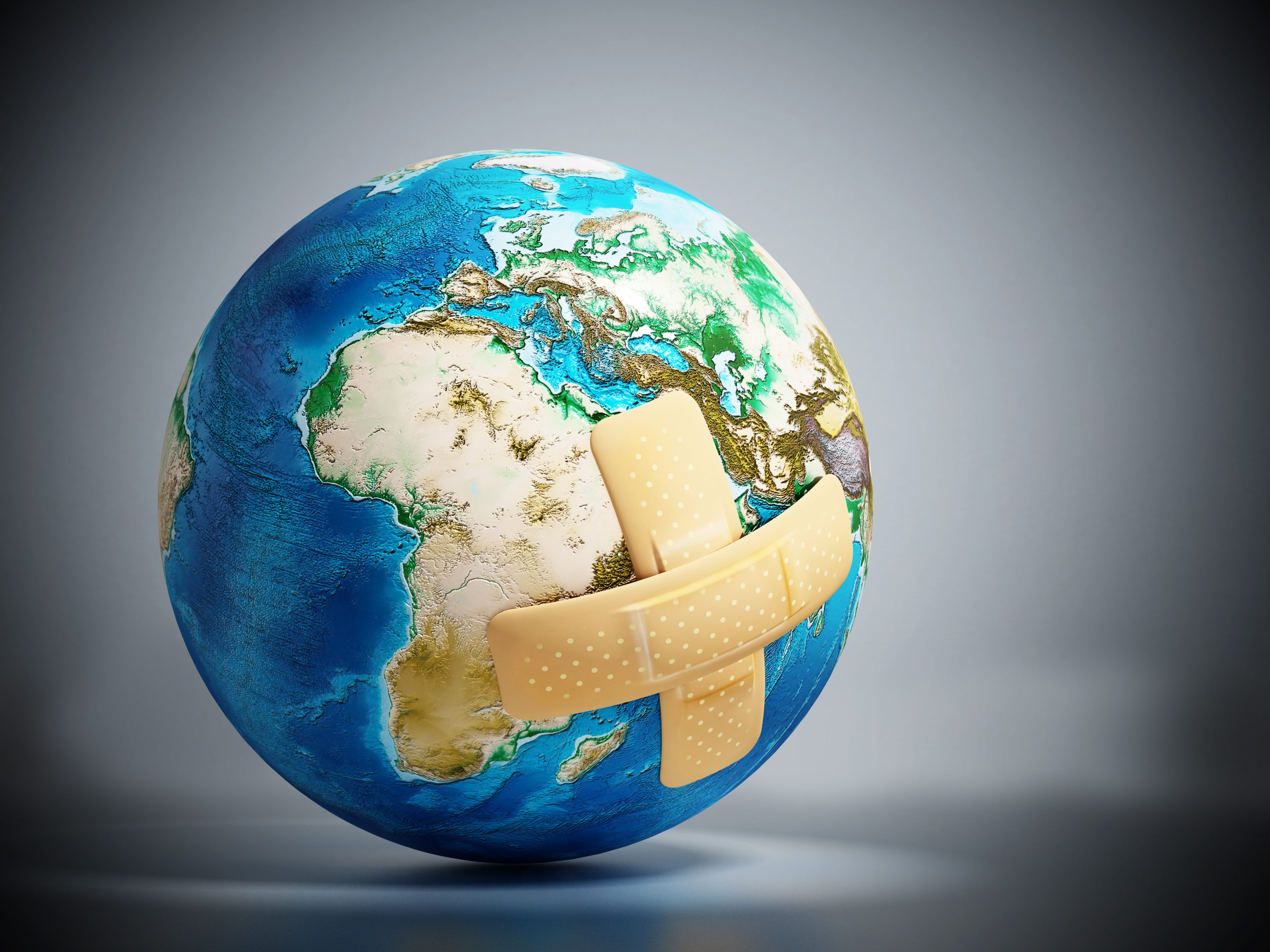 A small globe of the Earth, with two sticking plasters on it.